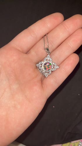 Customer holding the star-shaped Starburst Zircon Cremation Pendant with its colorful opal center.