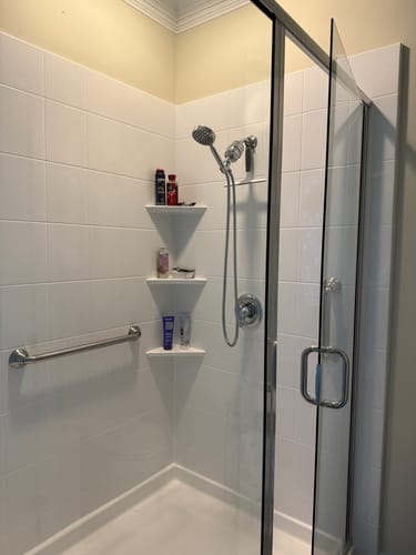 Reviewer's installed Handheld Shower Head Set and filter in a clean, white tiled shower stall.