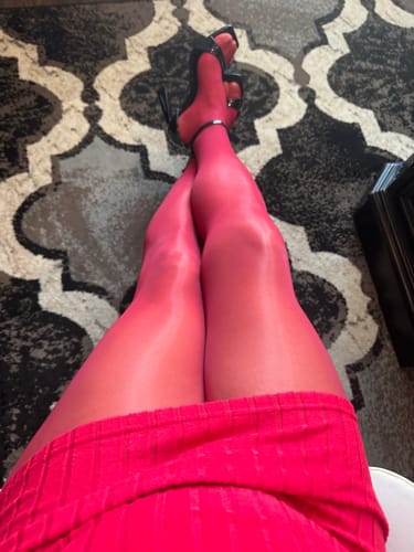 Close-up of a customer's crossed legs, showing the shiny finish of the berry-colored PLAY seamless tights.
