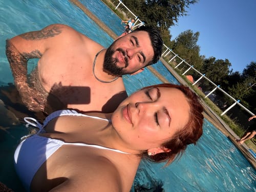 Cliente usando su Cadena Cuban Link 8mm en una piscina con una acompañante.
