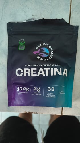 Cliente mostrando el empaque negro de Creatina Monohidrato con la parte superior abierta.