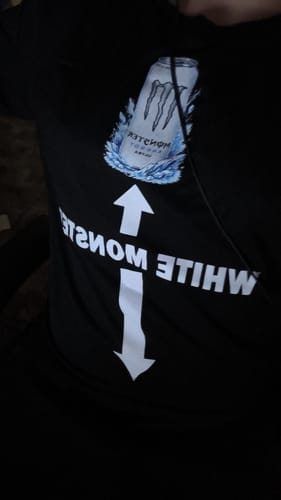 Kunde trägt das schwarze WHITE MONSTER Premium Shirt und zeigt den Aufdruck in einer Nahaufnahme.