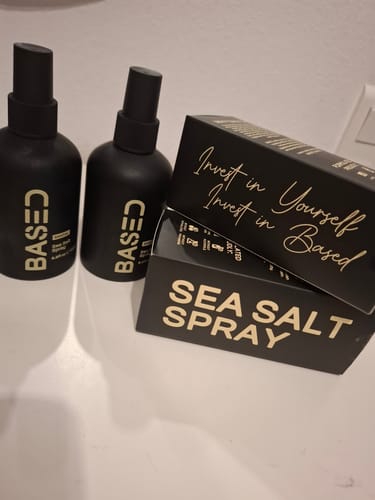 Reviewer's two black bottles of Sea Salt Spray next to their black product boxes on a white surface.