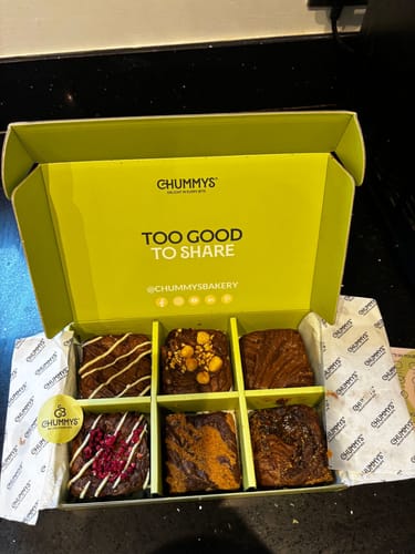 Customer's open box showing a mixed selection of six postal brownies with various delicious toppings.