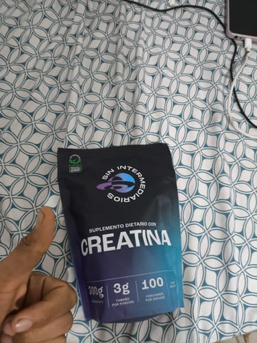 Cliente mostrando el empaque de su Creatina Monohidrato con un pulgar arriba en señal de aprobación.