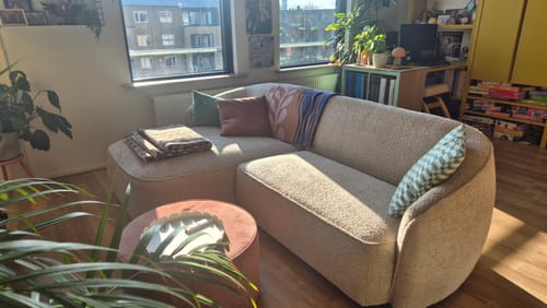 Klant toont de compacte Chubby hoekbank in een zonnige woonkamer.