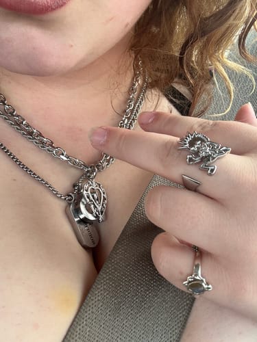 Close-up of a customer wearing multiple silver necklaces and three detailed rings from Hard Jewelry.