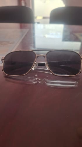 Customer's Co-Pilot wayfarer sunglasses with a silver frame and black lenses resting on a table.