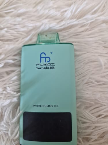 Kunde zeigt den mintgrünen Fumot Tornado 35k Vape in der Geschmacksrichtung „White Gummy Ice“ auf einer flauschigen Oberfläche.
