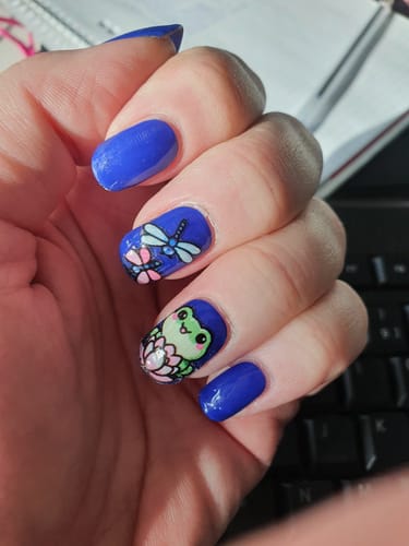 Kundenfoto der königsblauen 'Royal Curtsy' UV-Gelfolien, die mit Frosch- und Libellen-Nageltattoos verziert sind.
