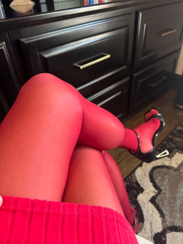 Close-up of a reviewer sitting, highlighting the glossy texture of the berry-colored PLAY seamless tights.