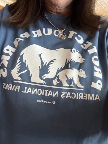 Close-up of a reviewer wearing the blue Protect Our Parks Tee, showing the white bear graphic.