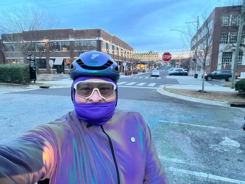 Reviewer wearing the reflective GLOWMOTION JACKET and helmet while cycling on a city street at dusk.