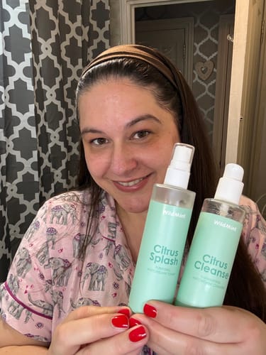 Reviewer smiling while holding two bottles from the 5-Step Clear Skin Kit.