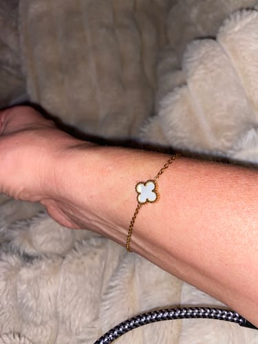 Ein Kunde trägt das Überraschungsgeschenk, ein goldenes Armband mit weißem Kleeblatt-Anhänger, am Handgelenk.