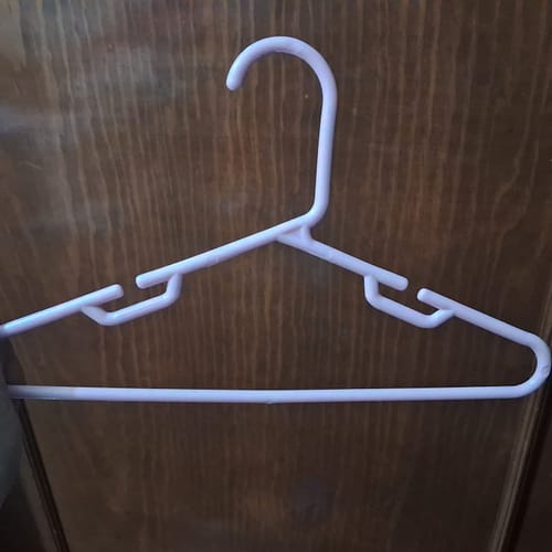 Cliente muestra un gancho infantil Inkanto de plástico rosa colgado en una puerta de madera.