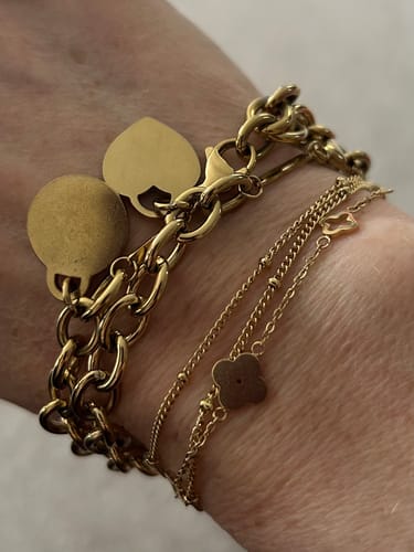 Close-up of a reviewer's wrist wearing the gold Chunky Disc Bracelet layered with other thin bracelets.