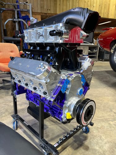 Customer's Motion Raceworks Bare Billet LS Valve Covers installed on a custom purple engine build on a stand in a garage.