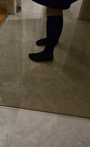 Recensent som visar passformen på ett par svarta Diasocks stödstrumpor på sina vader.