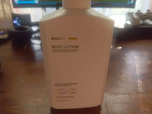 Customer's white bottle of Based Santal Body Lotion standing on a wooden desk.