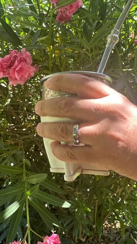 Cliente luciendo su Anillo Minimal en la mano mientras sostiene una taza al aire libre.