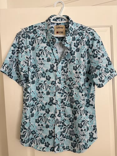 Customer's blue Disney "Aloha Pal" shirt on a hanger, showing the tropical pattern with Mickey Mouse.
