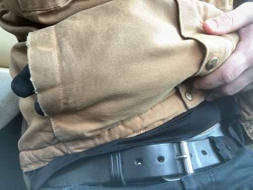 Close-up of a reviewer wearing the sturdy, black Gunner belt with a silver buckle.