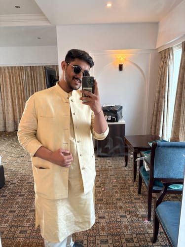 Reviewer wearing the Captain gold and black round sunglasses while taking a mirror selfie indoors.