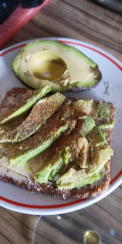 Rezensent zeigt eine aufgeschnittene Hass Mini Bio Avocado auf einem Brot und daneben eine Avocadohälfte.
