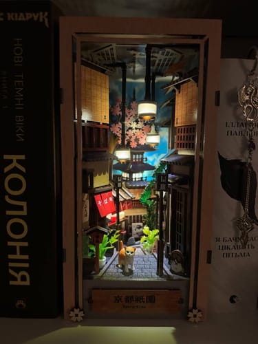 Customer's assembled Kyoto Gion Book Nook Kit, illuminated and nestled on a bookshelf between two books.