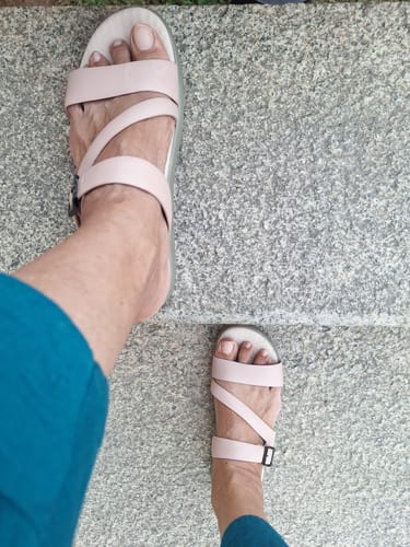 A top-down view of a reviewer wearing the light pink Frido Cloud Comfort Sandals on stone steps.