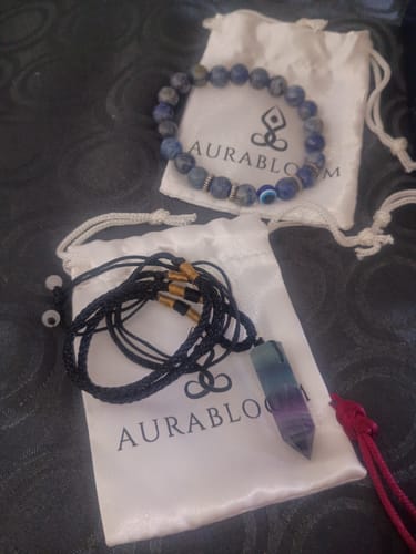 Customer's blue crystal bracelet and purple pendant necklace from the VIP Crystal Club, shown on branded bags.