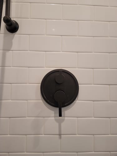 Reviewer's matte black 2-Handle Trim installed on a white subway tile shower wall.