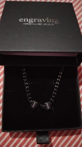 Customer's black steel Legacy Necklace with two engraved beads resting in its presentation box.