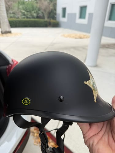 Customer holding a matte black Polo Switchback helmet customized with a sheriff's badge. An XL size sticker is on the side.