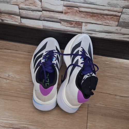 Customer's pair of white and black adidas Adizero Boston 13 running shoes with purple details on a floor.