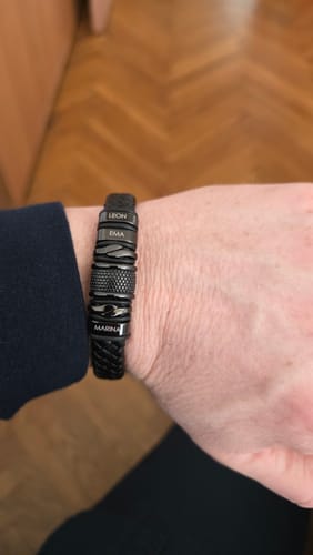 Reviewer wearing the personalized black bracelet on their wrist, engraved with the names Leon, Ema, and Marina.