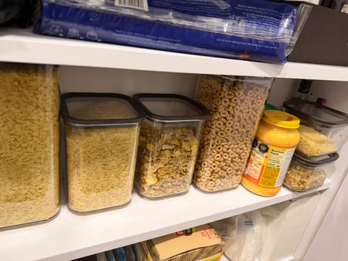 Cliente muestra los contenedores de plástico transparentes llenos de comida seca en una alacena.