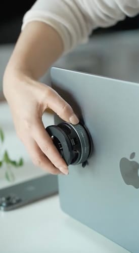 Customer attaching the black MagPro Magnetic Phone Holder to the back of a silver MacBook.