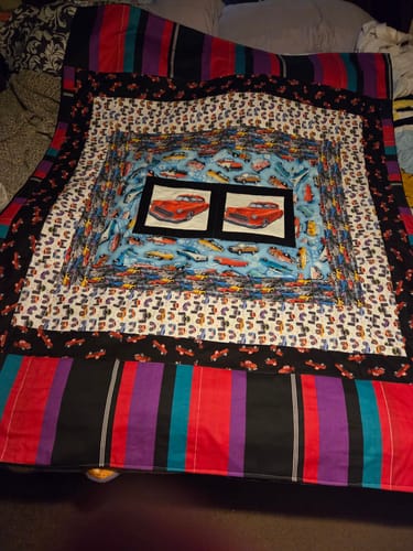 Customer's finished quilt using two Vintage Red Car Fabric Panels as the centerpiece surrounded by other car-themed fabrics.