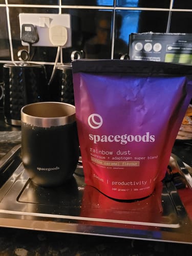 Customer's bag of Rainbow Dust in coffee caramel flavour, placed next to a black branded tumbler on a kitchen tray.