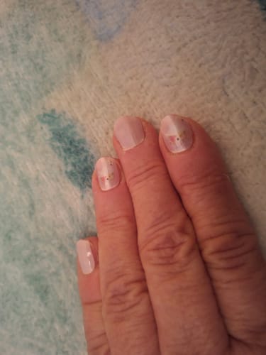 Hand einer Rezensentin, die die neutralen 'Lightest Tone' Nagelfolien mit einem dezenten Muster trägt.