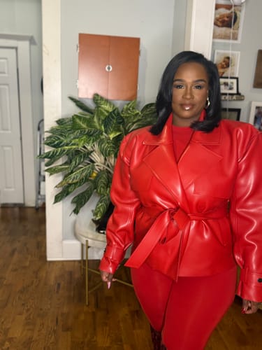 Reviewer wearing the red Vegan Leather Cropped Trench Jacket, tied at the waist in a home setting.