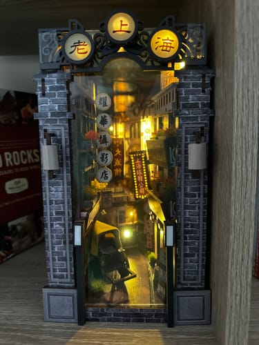 Customer's completed Old Shanghai Book Nook Kit, beautifully lit from within and displayed on a bookshelf.