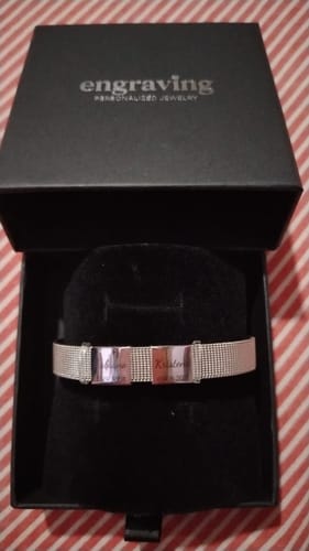 Customer's silver Lux Bracelet with two engraved pendants, shown inside its black presentation box.