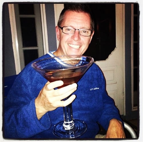 Reviewer smiling while holding a very large ruby red martini made with Deep Eddy Vodka.