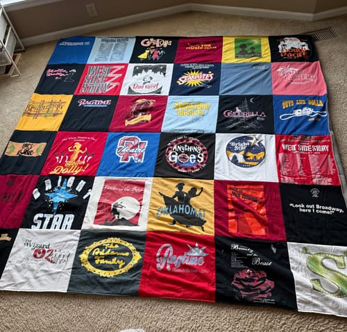 Customer's large Project Repat T-Shirt Quilt on the floor, made from various musical theater t-shirts.