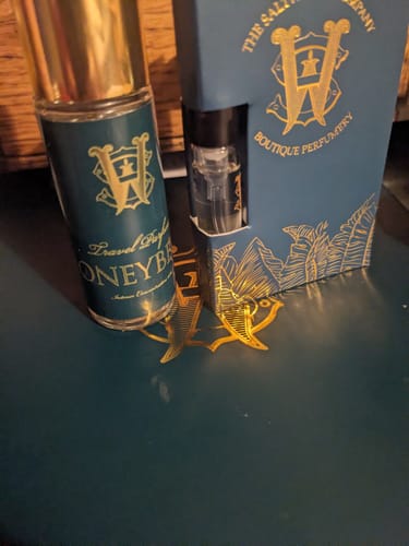 Reviewer's Honeyberry travel perfume and sample vial displayed next to its blue and gold box.