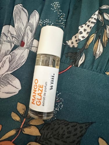 Customer's Mango Glaze rollerball bottle pictured on a floral fabric.
