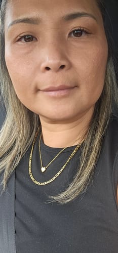 Reviewer wearing the layered gold Positano Necklace Bundle against a black top.